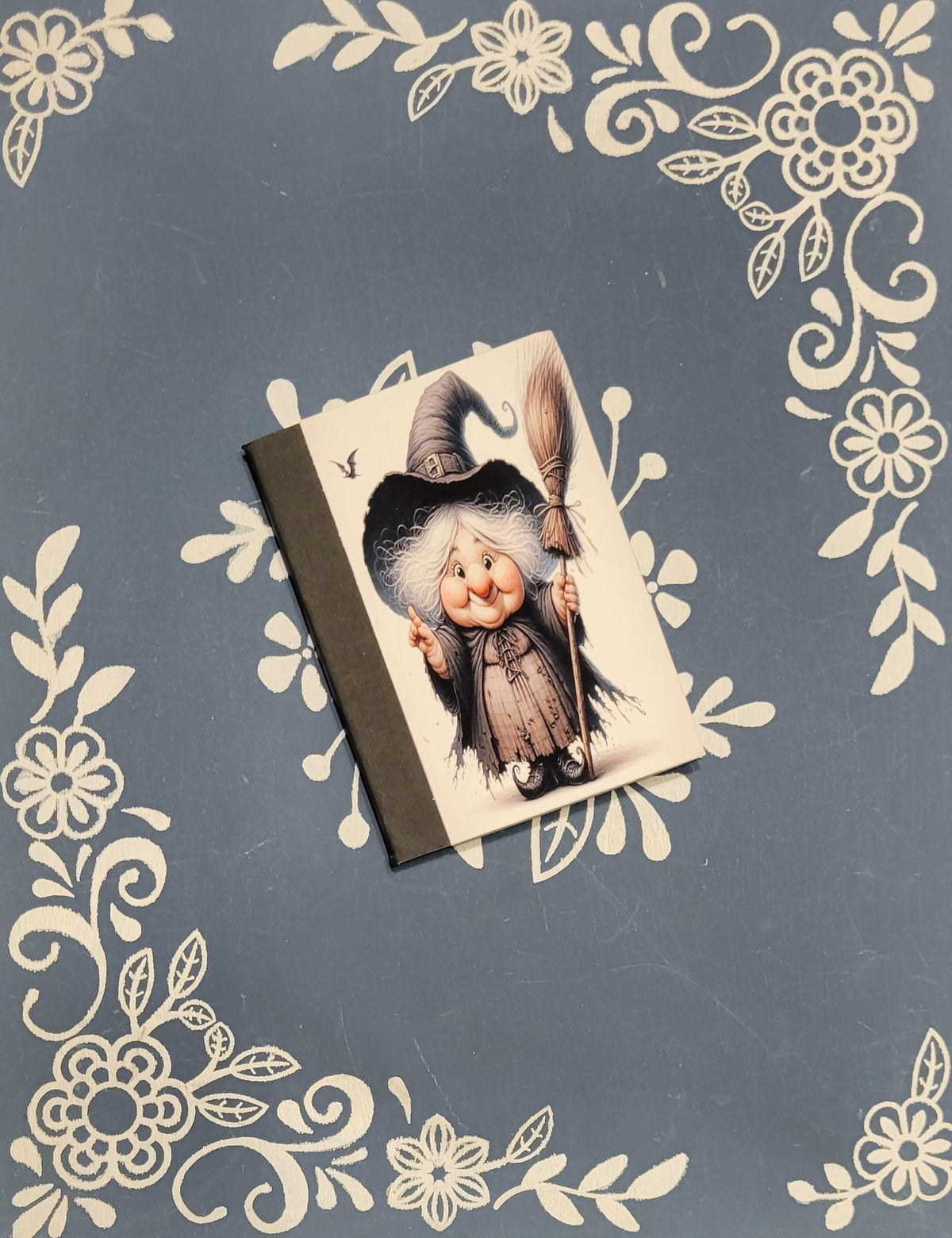 Vintage-style illustration of a witch on a decorative background with floral patterns.