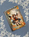 Covered notebook featuring a whimsical illustration of a fall fairy surrounded by warm autumn leaves on a rustic desk.