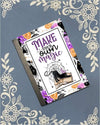 Covered notebook featuring a whimsical illustration of a witchy black cat and the quote Make Your Own Magic on a dark workspace desk.