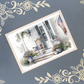 Decorative postcard with a porch scene featuring American flags on a blue background with floral border.