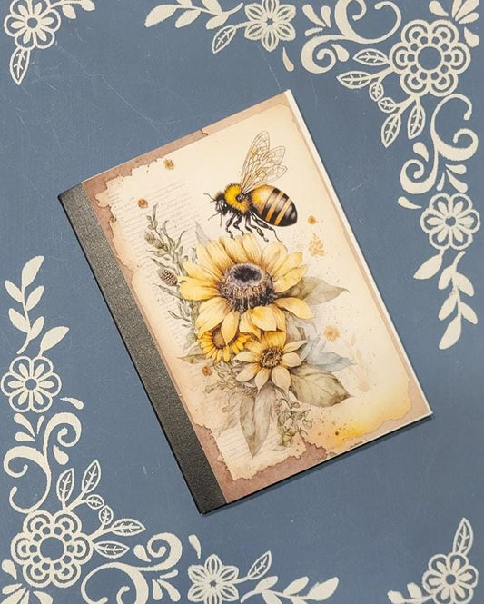 Notebook with sunflower and bee design on a decorative blue background