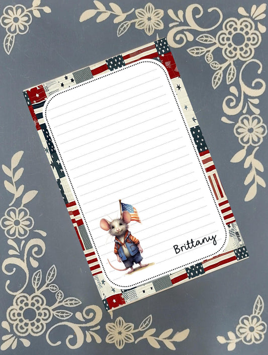 Personalized custom notepad featuring a cute, whimsical patriotic USA mouse illustration with a personalized name on a rustic desk.